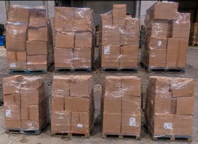 de nombreux cartons empilés sur des palettes dans un entrepôt