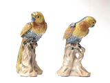two figurines of birds sitting on top of a tree stump