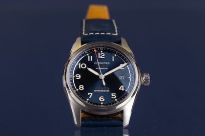 une image montrant un gros plan d'une montre posée sur une surface bleue