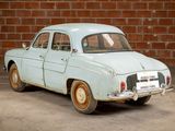 a old blue car parked in front of a brick wall