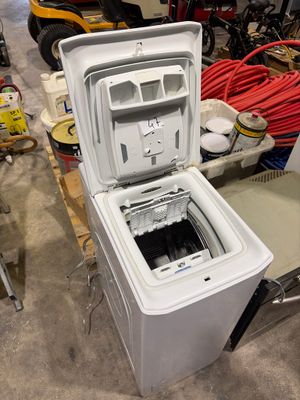 un réfrigérateur blanc posé dans une pièce où se trouvent de nombreux outils