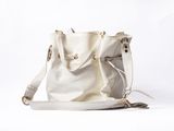 beige leather handbag with tassel on white background with copy space