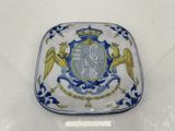 une assiette bleue et blanche sur laquelle est représenté un blason