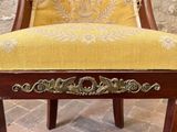 a chair with a yellow upholstered seat on a brick floor