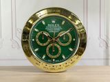 a gold clock with a green face on a wooden table