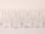 six clear glasses lined up in a row on a white surface