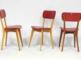 trois chaises rouges placées les unes à côté des autres sur une surface blanche
