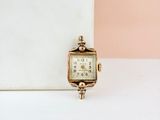 une petite montre en or posée sur une table blanche