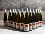 several bottles of wine are lined up in a row in front of a stone wall