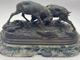 sculpture en bronze représentant deux sangliers en train de se battre, posée sur un socle en pierre