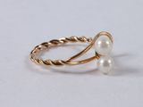 a close up of a gold ring with two pearls on it