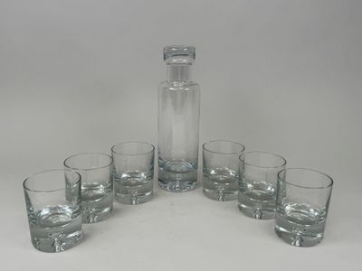 six verres et une carafe posés sur une table