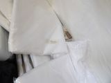 a pile of white pillows and sheets on a bed