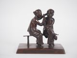 a bronze statue of two children sitting on a bench