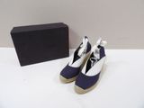 une paire de chaussures bleues et blanches posée à côté d'une boîte sur une surface blanche
