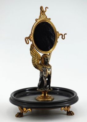 une statue représentant un ange tenant un miroir posé sur un plateau