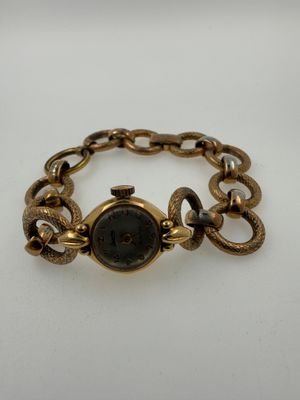 a close up of a watch on a chain on a white surface