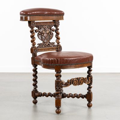 une chaise ancienne en bois, avec une assise en cuir marron et des pieds en bois