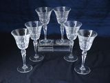 six verres à vin posés sur un présentoir posé sur une table