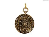 a black and gold pendant with a floral design on it
