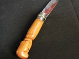 a close up of a knife with a wooden handle on a black cloth