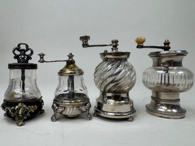 three silver and glass coffee grinders and one with a wooden handle