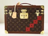 une valise marron et rouge posée sur une surface blanche