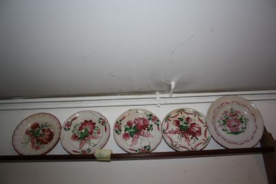 five plates on a shelf that have flowers painted on them