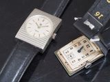 two watches sitting on a black table next to each other