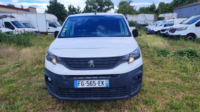 La camionnette blanche est garée dans l'herbe, devant d'autres véhicules.