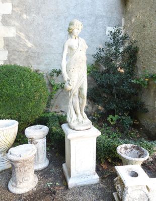 une statue représentant une femme debout à côté de deux vases