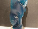 une sculpture bleue représentant le visage d'une femme, posée sur un socle