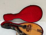 an old guitar with a red case sitting on a white surface