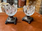 two glass vases sitting on a table in front of a window
