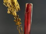 a red vase with a gold leaf sticking out of it