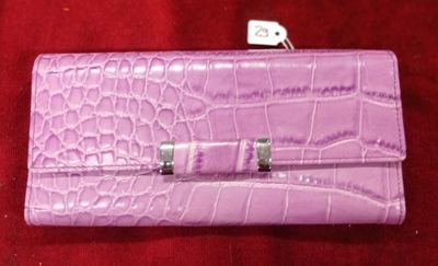 sac à main en cuir d'alligator violet avec des fermoirs argentés sur fond rouge