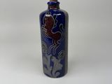 a blue and white vase with a bird on it on a white surface