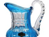 a blue glass pitcher with a handle on a white background
