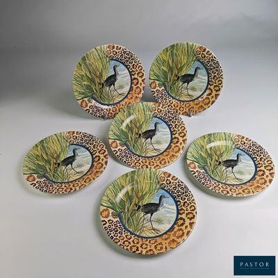 quatre assiettes sur lesquelles sont peints des oiseaux, posées sur une surface blanche