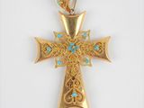un gros plan d'une croix en or ornée de pierres de turquoise