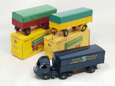 trois camions miniatures posés les uns à côté des autres sur une surface blanche