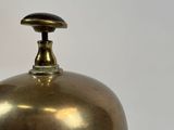an antique brass bell with a black knob on a white background