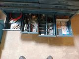 a person standing in front of a desk with a drawer full of tools