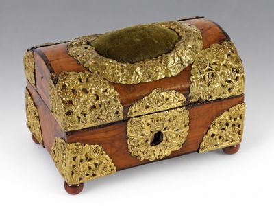 une boîte en bois richement décorée, ornée de motifs dorés sur un fond blanc