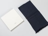 une écharpe noire posée à côté d'un livre blanc sur une surface blanche