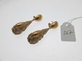 une paire de boucles d'oreilles dorées ornées de cristaux verts et d'une étiquette de prix
