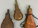 three antique copper bottles with handles and a leather case