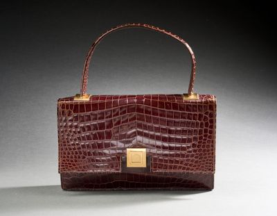 a brown crocodile skin purse with a gold clasp