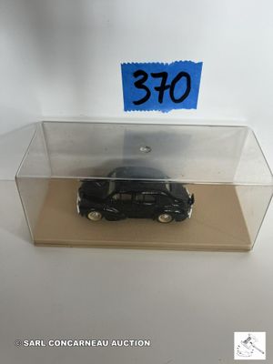 une petite voiture noire dans une boîte transparente sur laquelle est collé un autocollant bleu
