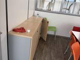 tables and chairs in a room with a window and a refrigerator